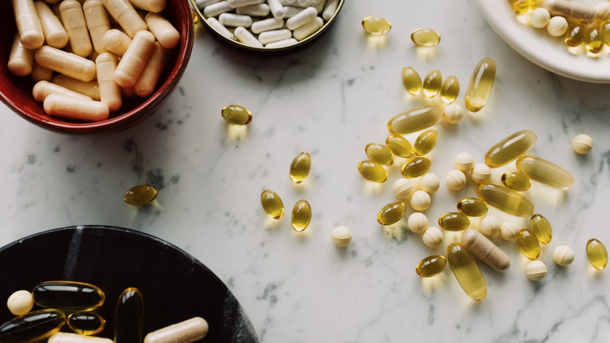 A flat lay of diverse capsules and supplements on a marble countertop, showcasing health and wellness products.